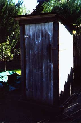 The homemade outhouse with the door closed